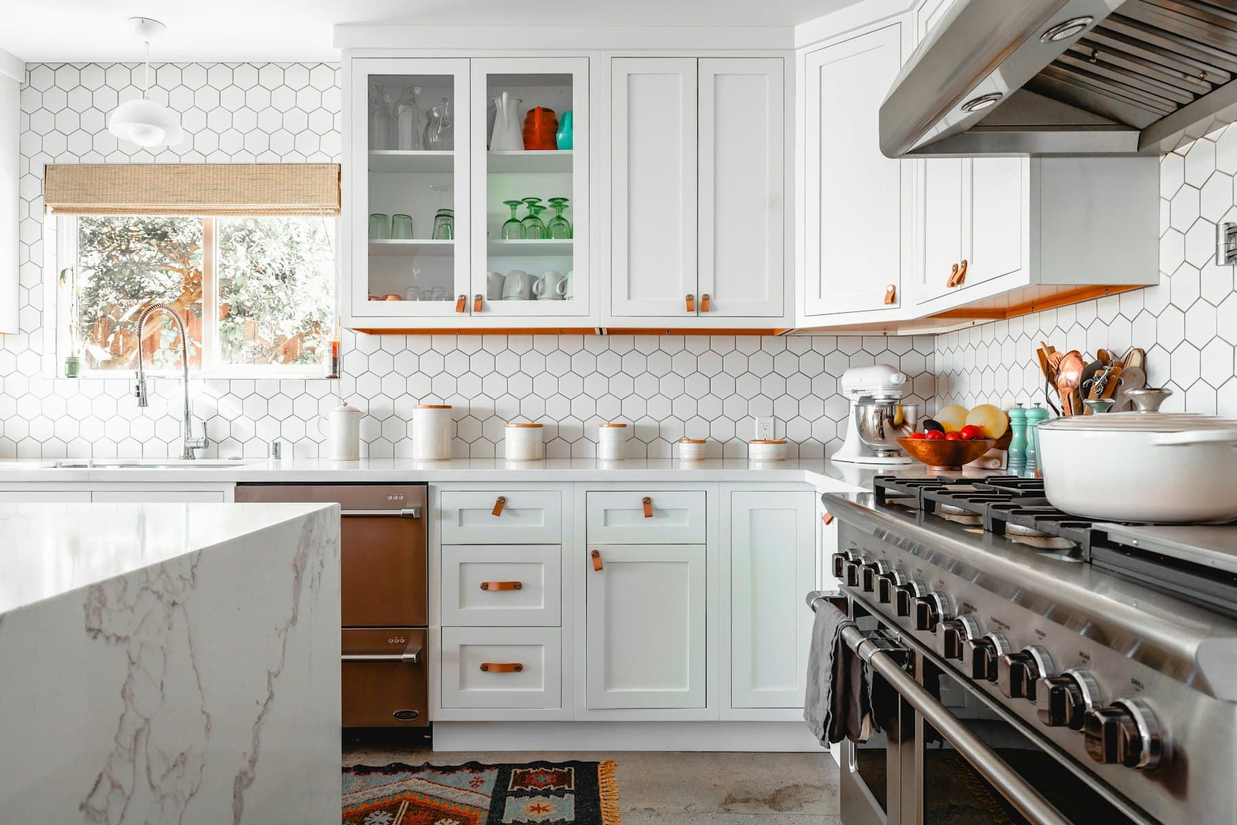 A finished kitchen with white cabinets and hexagonal wall tiles
