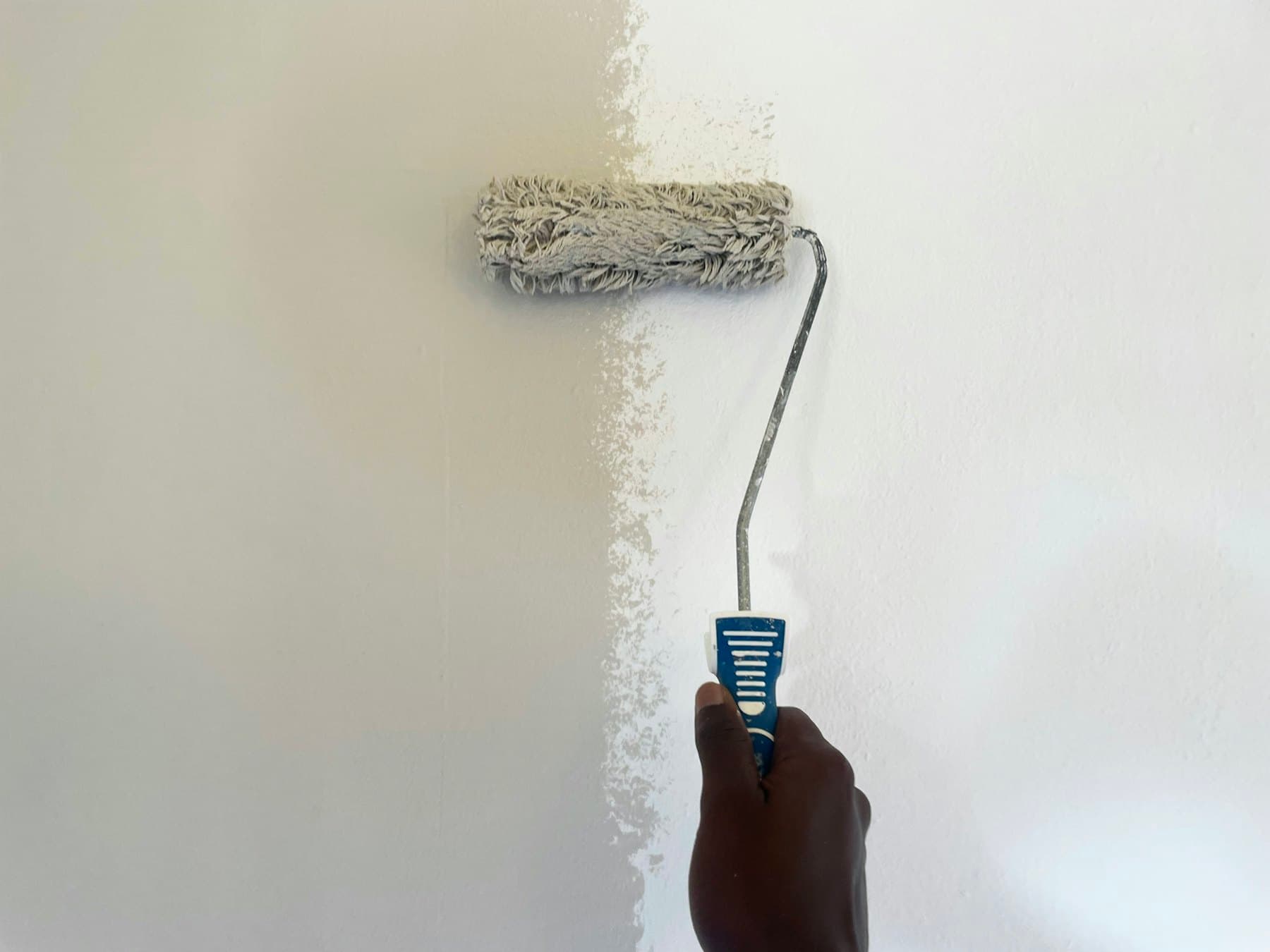A wall being painted white with a roller